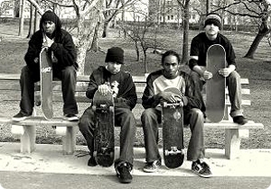 Vier Jugendliche mit Skateboards sitzen auf einer Parkbank in New York. Copyright: Panos Manologlou